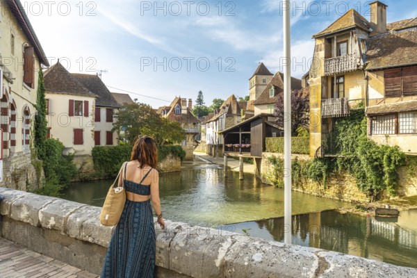 Young woman admiring the saleys river flowing through the picturesque village of salies de bearn, a popular tourist destination in the pyrenees atlantiques region of france