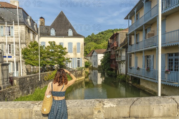 Tourist is enjoying the view of the saleys river and its colorful houses in the charming village of salies de bearn, a popular destination in the pyrenees atlantiques region of france