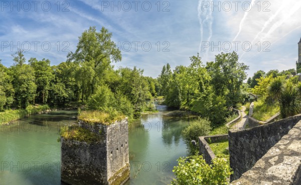 Scenic view of the gave d'oloron river with a ruined bridge pier and lush vegetation in sauveterre de bearn, a charming medieval town in the pyrenees atlantiques region of france