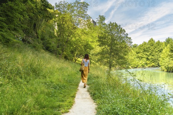 Tourist enjoying a peaceful walk along the gave d'oloron river in sauveterre de bearn, a charming medieval village in the pyrenees atlantiques region of france