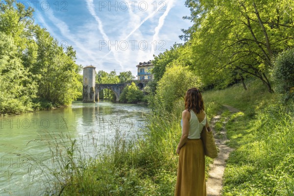 Woman enjoying summer vacations in french countryside admiring the medieval bridge and tower of sauveterre de bearn in the pyrenees atlantiques
