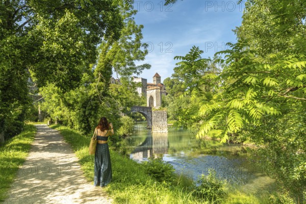Tourist taking pictures of the gave d'oloron river and the medieval bridge and castle of sauveterre de bearn in france, a popular tourist destination
