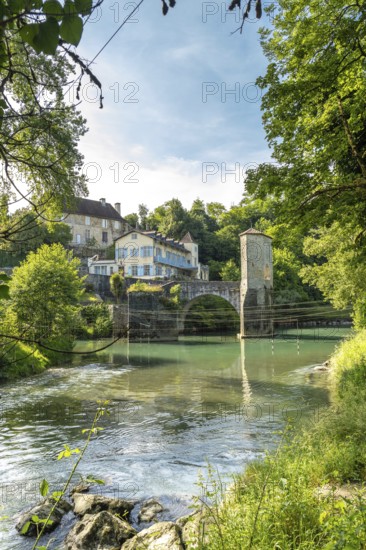Scenic view of a historic stone bridge crossing the gave d'oloron river, surrounded by traditional houses and lush greenery in the charming village of sauveterre de bearn, france