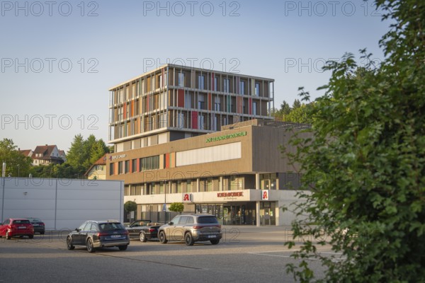 Modern building structure next to a car park with several cars in the sunlight, Nagold, district of Calw, Black Forest, Germany
