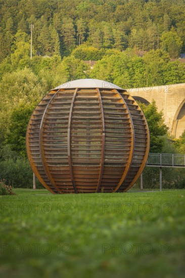 Large wooden ball in a park, surrounded by green grass and trees in the background, Nagold, district of Calw, Black Forest, Germany
