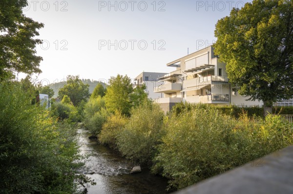 Residential building next to a river, surrounded by trees on a summer evening, Nagold, district of Calw, Black Forest, Germany