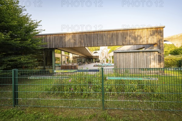 Modern building with wooden wall and garden, surrounded by a green fence in sunshine, Nagold, Landkreis Calw, Schwarzwald, Germany