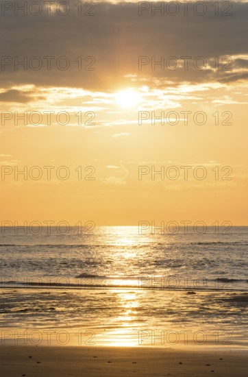 Picturesque sunset over the sea with grey clouds and golden light, sun star, clouds, reflecting light on the shining water and calm atmosphere, warm atmosphere, sea in soft colours, peaceful, orange and gold, wide horizon, sandy beach, mudflats in the foreground, cloud gap, dark clouds, calm sea, island dune, Helgoland, district Pinneberg, Schleswig-Holstein, North Sea, Germany