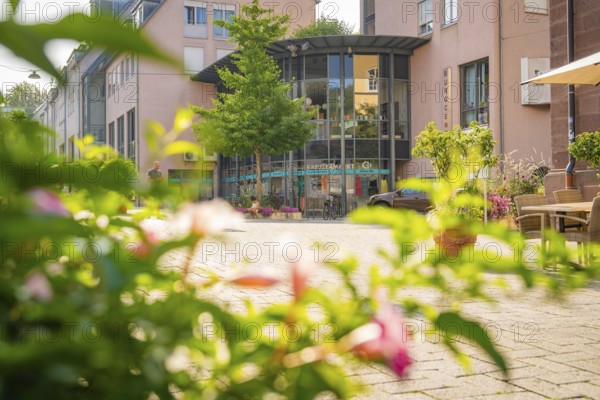 Street scene with a modern building surrounded by green vegetation and warm light, Nagold, district of Calw, Black Forest, Germany