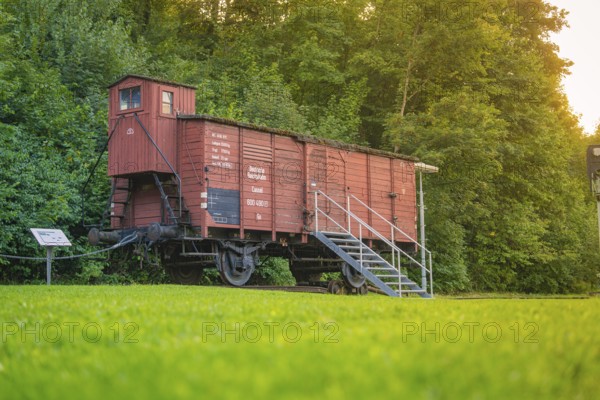 A red goods wagon with steps, green meadow and forest next to it. Nostalgic railway environment, Nagold, district of Calw, Black Forest, Germany