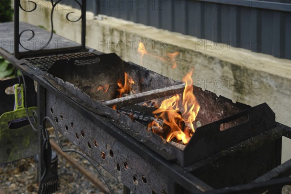 Wood is burning in the grill. The backyard setting features a rustic grill, hinting at a gathering with friends and family