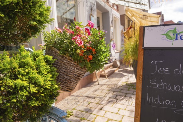 Basket of flowers on a bicycle in front of a shop window in sunny weather, small town of Perle Calw, district of Calw, Germany