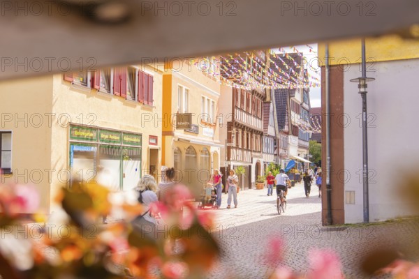 Lively street in a charming old town with cyclists and passers-by, surrounded by historic houses, small town pearl Calw, Black Forest, Germany