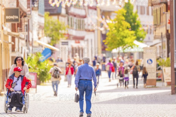 People stroll through a lively, sunny pedestrian zone with historic buildings, small town pearl Calw, Black Forest, Germany