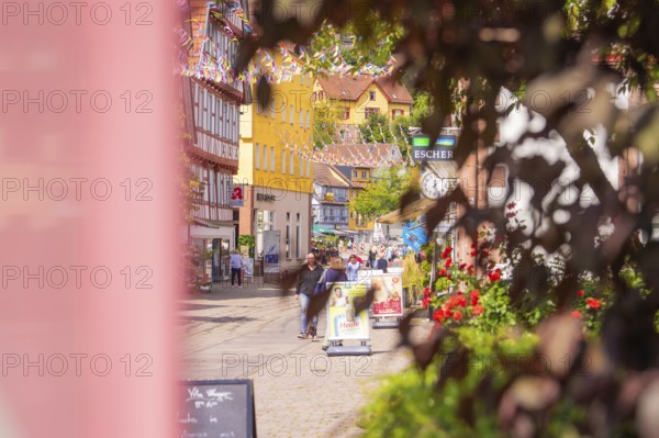 Old town street with full shops and colourful decoration, lively with passers-by, small town pearl Calw, Black Forest, Germany