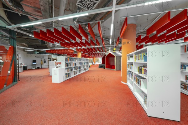 A modern library with eye-catching red and white elements creates a lively atmosphere, Munich, Germany