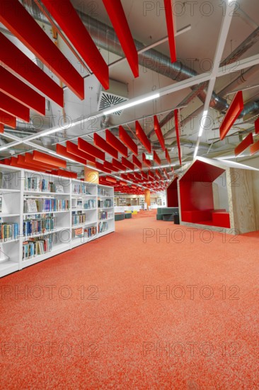 Modern library with red accents, bookshelves and comfortable reading corners, Munich, Germany