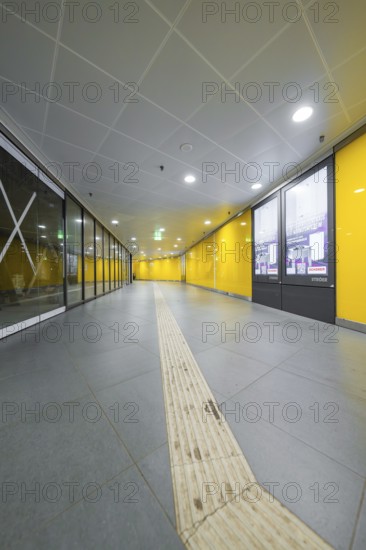 A modern station corridor with yellow walls and a grey floor conveys cleanliness, Munich, Germany