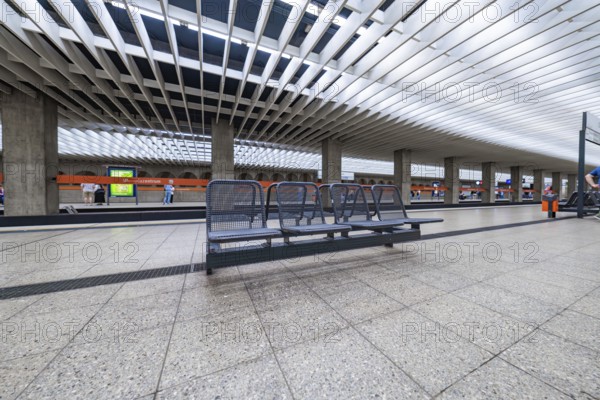 Spacious modern railway station with benches under a glass roof, Munich, Germany