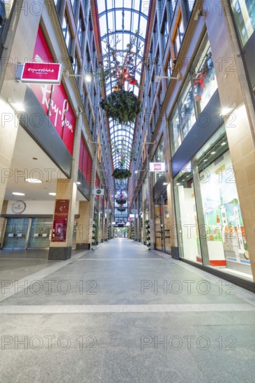 Long shopping arcade with glass roof and illuminated shop windows in an urban atmosphere, Munich, Germany