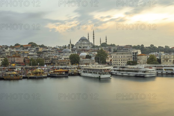 Ferryboats navigating the golden horn at sunset, with the majestic suleymaniye mosque dominating the istanbul skyline, creating a picturesque urban landscape