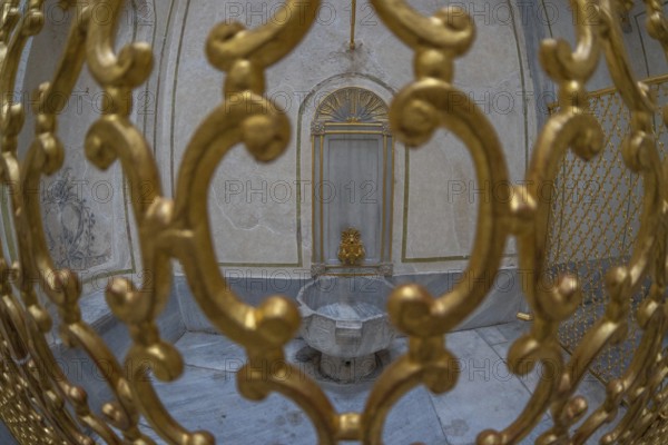 Ornate golden gate protecting a marble fountain inside a historical building in istanbul, turkey, showcasing the rich history and architecture of the city