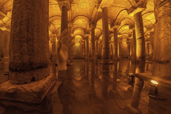 Giant hand sculpture rising from the water surface of the ancient basilica cistern in istanbul, turkey, creating a mystical atmosphere
