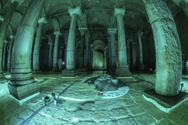 Green lights illuminating ancient columns, medusa's head and hand sculptures in basilica cistern, a famous landmark in istanbul, turkey