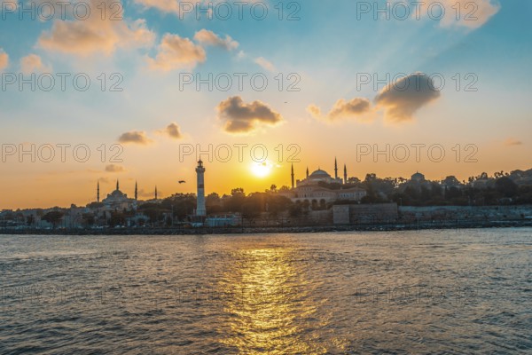 Golden sunset illuminating hagia sophia and ancient lighthouse in the bosphorus strait in istanbul, turkey, creating a picturesque cityscape