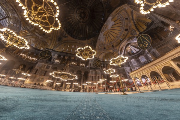 Wide angle view of the interior of hagia sophia in istanbul, turkey, showcasing its magnificent dome, intricate mosaics, and large chandeliers