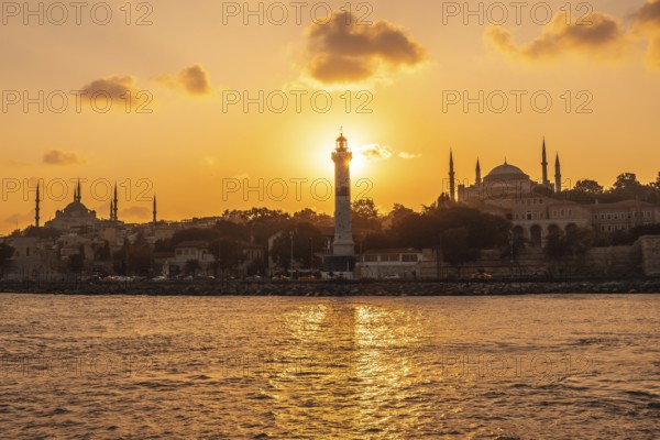 Scenic sunset over istanbul with prominent lighthouse, mosque and hagia sophia silhouettes, showcasing the city's beauty and rich history
