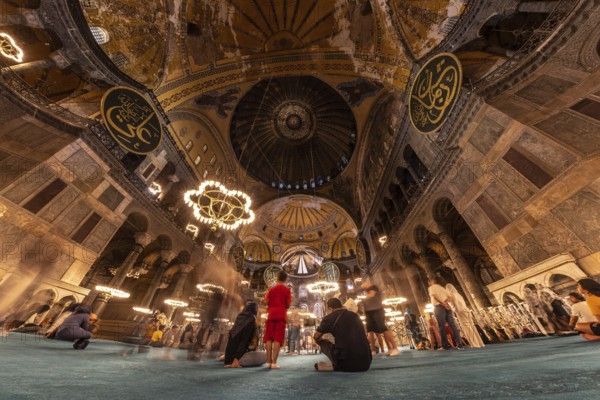 Tourists contemplating the impressive architecture and intricate details of the hagia sophia, a historical landmark in istanbul, turkey