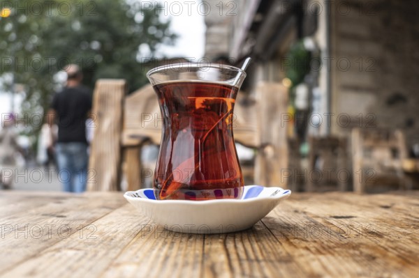 Steaming turkish tea, served in a tulip shaped glass, sits on a wooden table in a cafe in istanbul, offering a taste of turkish culture