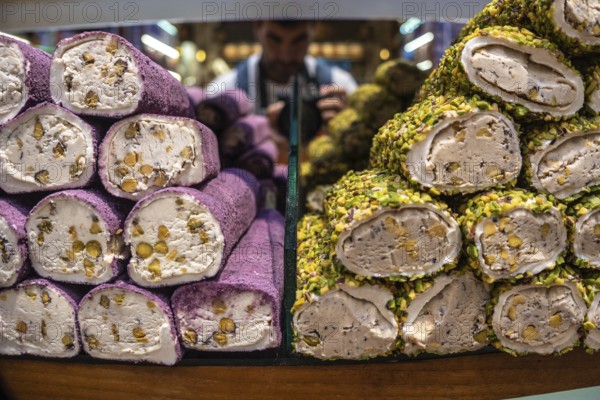 Colorful turkish delight lokum rolls, coated in pistachios and filled with walnuts, stacked on display in istanbul's vibrant spice market
