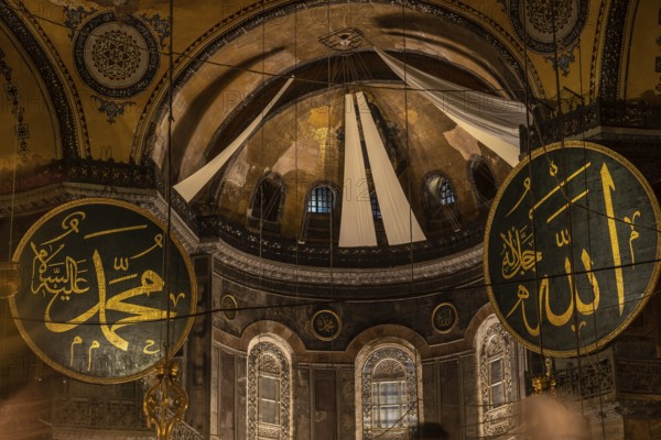 Interior view of hagia sophia showcasing islamic calligraphy, the central dome, and architectural details, illuminated by natural light