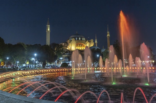 Colorful illuminated fountain jets dancing in front of the hagia sophia in istanbul, turkey, creating a magical night scene