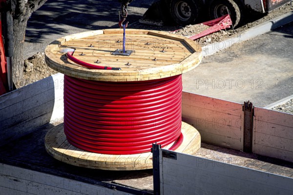Big red cable coil, rises for installation at the city construction site, no people