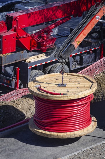 Big red cable coil, rises for installation at the city construction site, no people