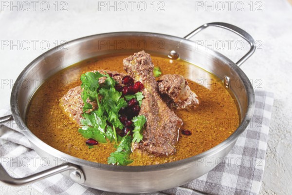 Fesenjan, an Iranian dish, stewed chicken, in a nut-pomegranate sauce, in a saucepan, light background, homemade, no people
