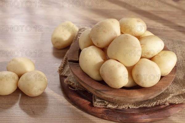 Boiled new potatoes, in a wooden bowl, on a rustic table, natural light, no people