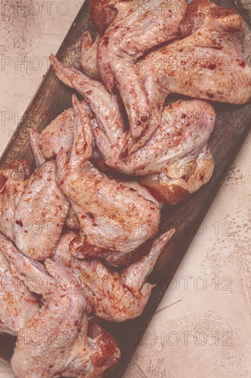 Chicken wings, marinated and laid out on a wooden platter, ready for cooking, grilling or baking, in a home kitchen, there are no people