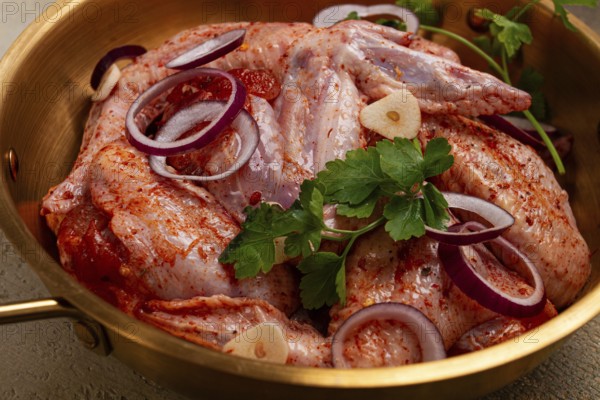 Chicken wings, in a brass saucepan, ready for cooking, grilling or baking, in a home kitchen, no people