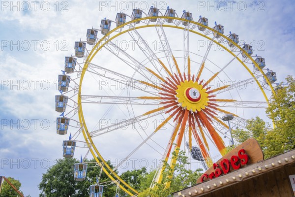 Colourful Ferris wheel with blue cabins, framed by fairground stands, Olympic Park, Munich, Germany