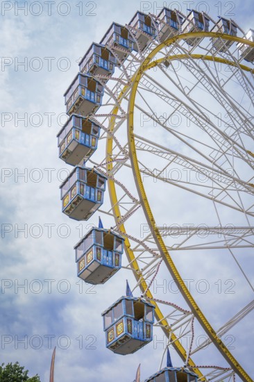 Ferris wheel with blue cabins rises into the cloudy sky, Olympic Park, Munich, Germany
