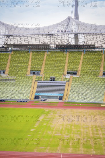 Detailed view of a stadium section with green seating area and roof structure in the background, Olympic Park, Munich, Germany