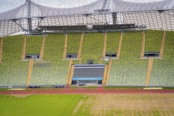 Detailed view of a stadium section with green rows of seats and striking roof background, Olympiapark, Munich, Germany