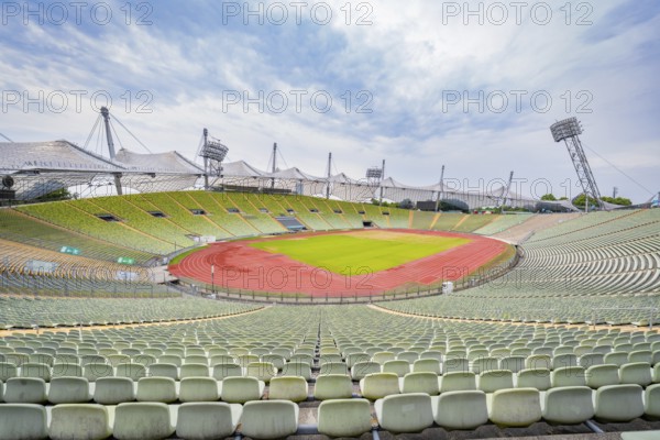Expansive view of a stadium with red and green colours under a cloudy sky, Olympiapark, Munich, Germany