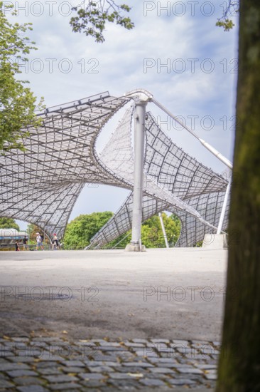 Modern architectural structure with lattice roof and a tree in the foreground, Olympiapark, Munich, Germany