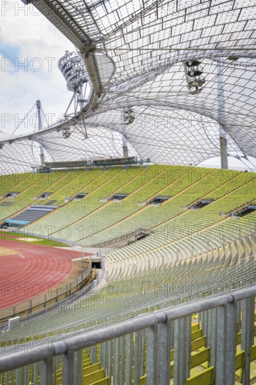 Green stadium with striking metal architecture and empty stands under a clear sky, Olympiapark, Munich, Germany