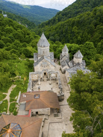 Aerial view of an old monastery complex surrounded by lush green forests, showing historical architecture, aerial view, Haghartsin Monastery, Hagarzin, left church Surp Astvatsatsin, right church Surp Stepanos and Surp Grigor and a gavit, Tavush Province, Armenia